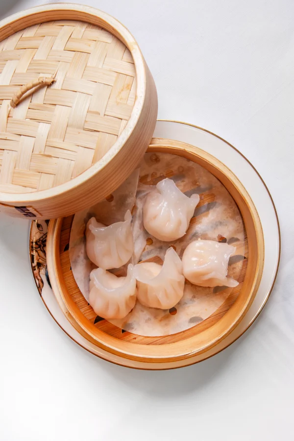 Empanadillas de langostino al vapor servidas en cesta de bambú tradicional